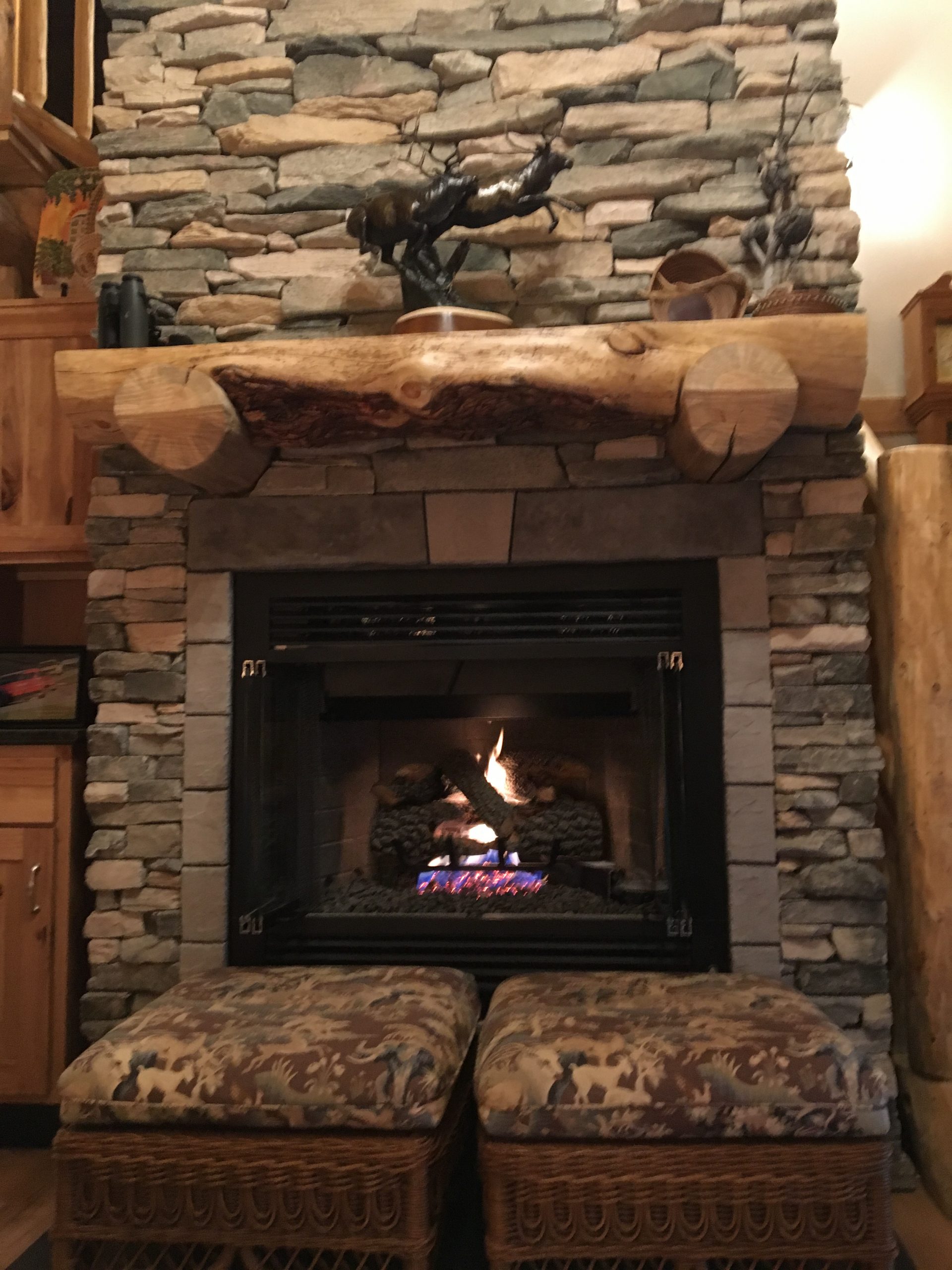 A handcrafted log mantle and stacked stone make a beautiful focal point in this log homes' great room.