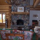 Cozy couch in front of custom river rock fireplace with log mantle in handcrafted Cedar log home.