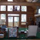 Great room of Cedar log home with river rock fireplace and glass wall with views to Montana forest.