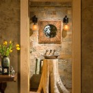 Flare base cedar stump with copper sink on top with stone wall behind viewed through open door.