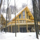 Exterior log home with prow front windows in winter