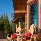 Two custom wood rocking chairs sit on deck in front of custom log home.