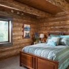 Handcrafted log home bedroom with cozy queen bed on white carpet.