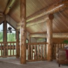 Log posts, ridgepole and purlins support pine ceiling in handcrafted log home.