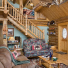 Interior of handcrafted log home with log stairs to loft