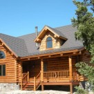 Exterior log cabin with gable dormer, covered porch and log railing