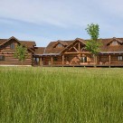 Large ranch style log home with log truss at entry and attached log garage.