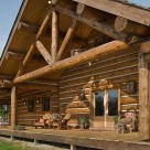 Close up photo of chink style ranch house porch with handcrafted log truss and log ceiling beams.