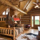 Log bed in loft bedroom of custom log home.