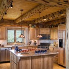 Custom kitchen in handcrafted log home with rustic log post and beams and pine t&g ceiling.