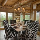 Zebra stipe chairs at dining room table in handcrafted log home with french doors showing view of southern forest.