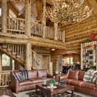 Handcrafted log home great room with massive antler chandelier, leather sofa's and log posts at loft edge supporint log roof beams.