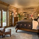 Basement bedroom with log siding interior, king size bed and french doors leading to patio outside.
