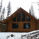 Exterior of log cabin with covered porch in winter