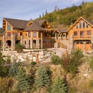 Exterior photo of luxury log home and guesthouse attached by breezway in mountain setting.