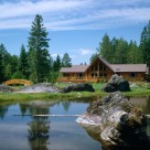 Exterior of custom log home with prow front viewed from across pond