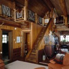 Interior of rustic log cabin with stairs to loft and Navaho rugs on log railings