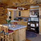 Log home kitchen with antique cook stove, blue tile counters and breakfast bar with log barstools.