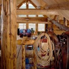View from loft in custom log home with saddle and lariat on log rail in foreground and great room below.