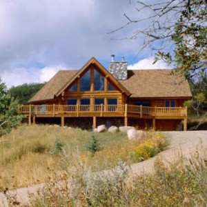 Exterior of log home with bay dining room and glass wall in great room