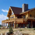 Exterior of handcrafted log home with large deck wrapped with log railings set on walk out basement.