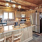 Beautiful kitchen with stone floors, stainless steel appliances, granite counter tops and custom cabinetry in handcrafted log home.