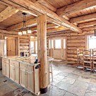 Kitchen and dining room in handcrafted log home with stone floors and log post and beams supporing loft floor above.