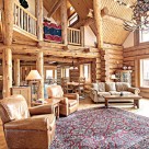 Interior of luxury log home with open kitchen, dining and great room. Log posts and beams support loft level and and exposed purlins for roof.