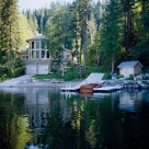 Luxury log home viewed from boat on Swan Lake, Montana. Massive octagonal front of home with log post and beams seperating windows.
