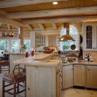 Classy kitchen and dining room in luxury log home with wide plank pine flooring, whitewashed logs, granite counters and exposed log ceiling beams.