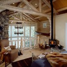 Open loft bedroom in luxury log home with view through soaring greatroom windows to Swan Lake, montana. Cathedral ceilings suported by whitewashed log trusses and exposed log beams.