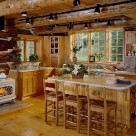 Kitchen in custom log home with vermont castings wood stove, center island with wine rack on end and track lighting above attached to massive log ceiling joists.