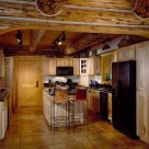 Custom kitchen cabinets and island in kitchen with hardwood floors in chink style log home.