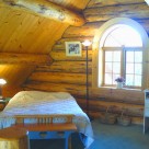 Loft bedroom with archtop window in custom log home