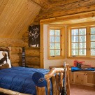 Walkout bay in luxury log home bedroom with log bed and blue comforter.