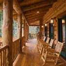 Cozy covered porch with log beams, log railings and log rocking chairs with views to Colorado aspen forest.