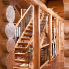 Cloes up photo of log posts and beam with log staircase and custom metal railings.