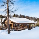 Dovetail log cabin with covered porches in winter.