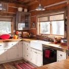 Kitchen in chink style dovetail log home with white cabinets and wood counter tops.