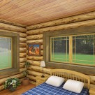 Rendering of log home bedroom with queen bed, blue and white comforter, end tables with lamps and views through windows to forest.