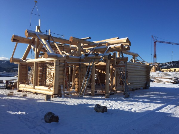 A custom log truss tops two large window openings in this handcrafted log shell.