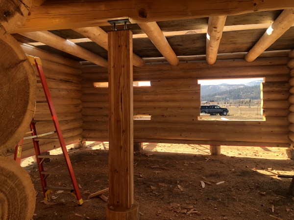 The interior of a full scribe log home under construction showing a stringer log and loft logs.