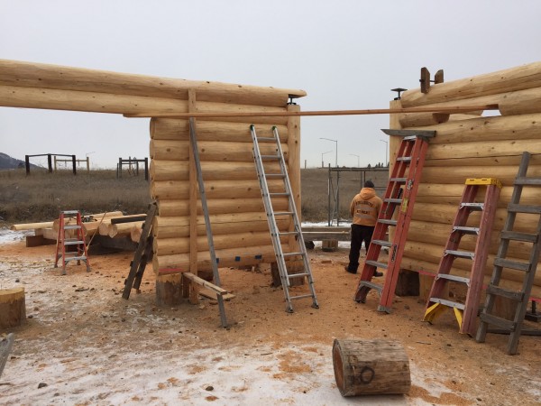 Handcrafted log walls stop at vertical columns which form the entry to a gazebo that will be built next.