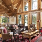 Log home greatroom with large windows between log posts