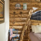Log home bedroom with log ladder to bunkbed and rocker